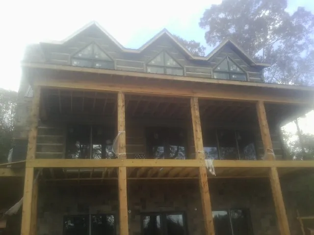 Dormers and porch framing on a large log home under construction — Roof Coating work by our crew in Tolovana Park