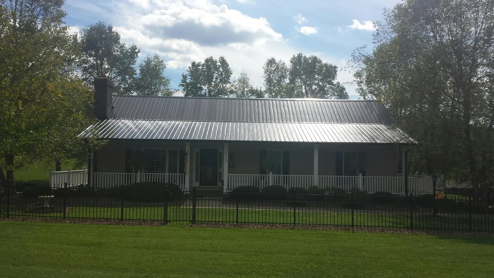 Gray metal roof on a brick ranch with a full width front porch — Gutter Guard Installation work by our crew in Tolovana Park