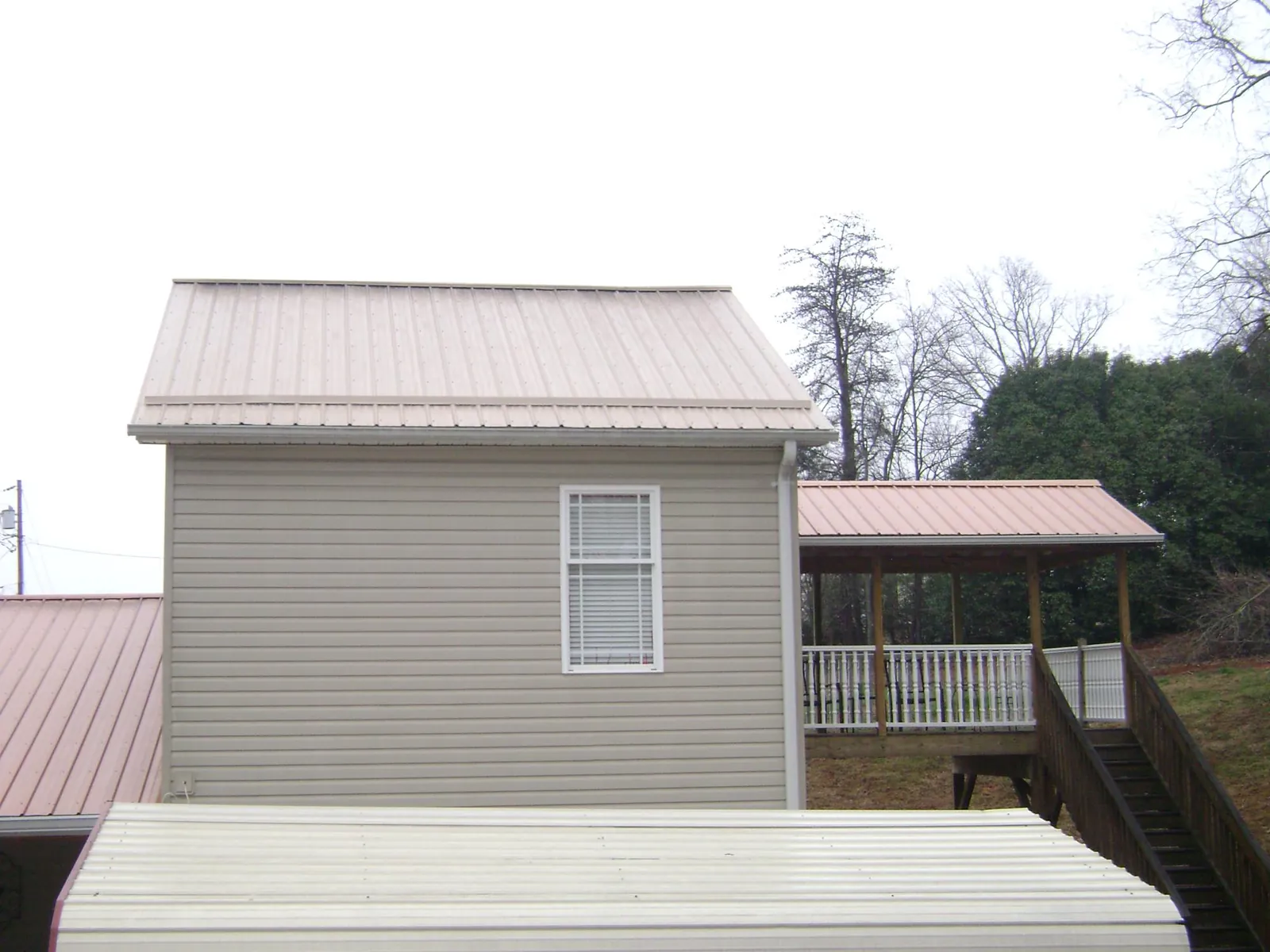 Tan metal roofs on a two story addition and attached porch, from a Roof Replacement job in Tolovana Park